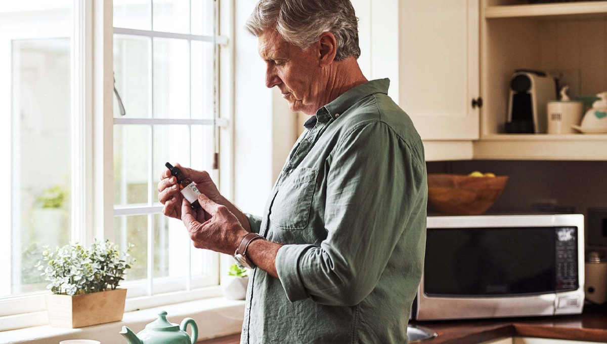 Medical Cannabis May Improve Symptoms of Depression and Anxiety: An elderly man holding a CBD bottle in his hands