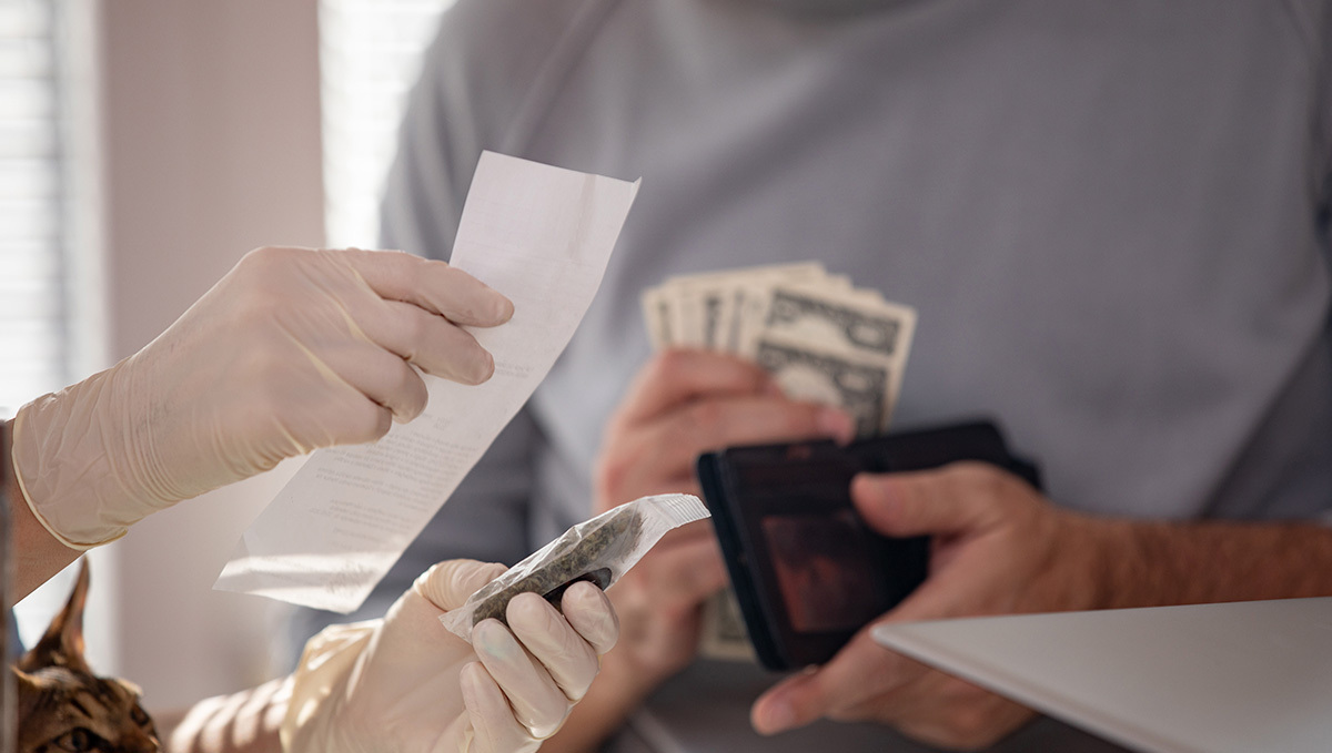 Two persons' hands as they exchange weed for cash in what seems like a legal dispensary Two persons' hands as they exchange weed for cash in what seems like a legal dispensary