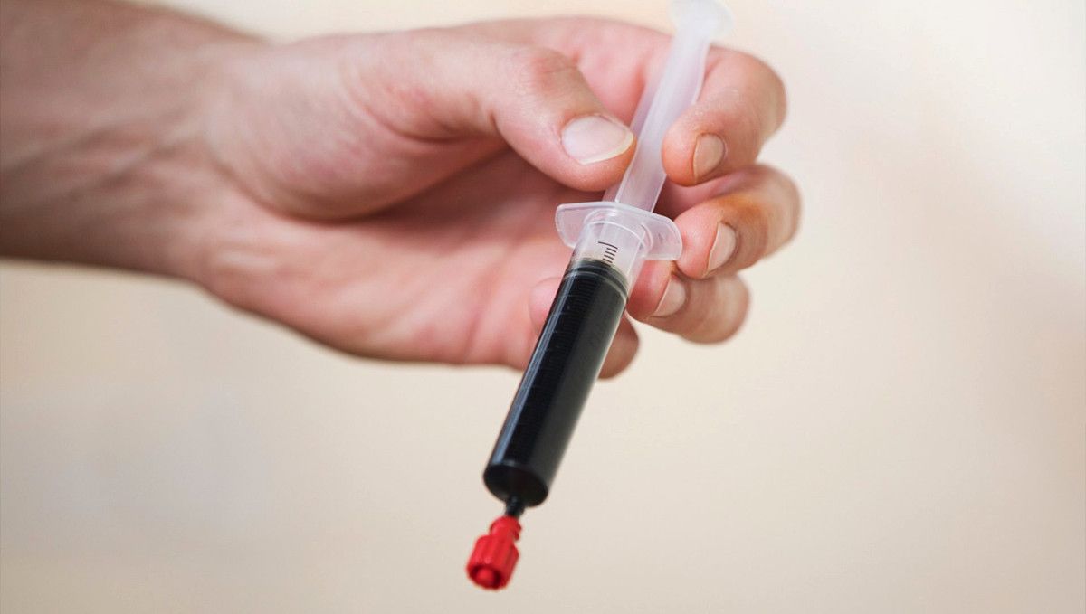 What is Rick Simpson Oil (RSO): Does It Work? A man's hands as he's holding a syringe with RSO